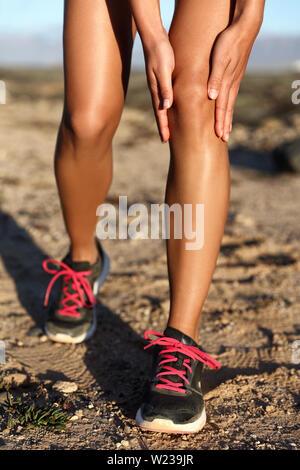 Runner Frau greifen schmerzhaft verletzten Knie schmerzen. Athlet Frau läuft außen mit Körperverletzung. Nahaufnahme der belastete Gelenk auf führen Sie im Sommer im Freien Natur. Fitness bein Unfall während cardio Workout. Stockfoto