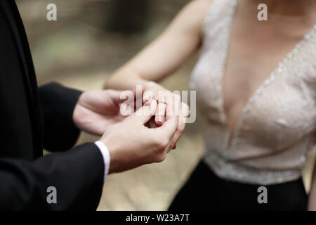Erschossen Sie Moment, wenn der Bräutigam den Ring einerseits eine junge Braut bringt. Stockfoto