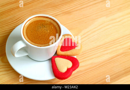 Heiße Tasse Kaffee mit ein paar herzförmige Plätzchen auf Holztisch mit Kopie Raum Stockfoto
