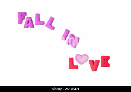 Das Wort verlieben in lila und rosa Alphabet geformte Gebäck und eine herzförmige Marshmallow candy auf weißem Hintergrund geschrieben Stockfoto
