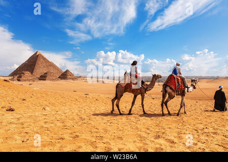 Touristen, Kamele, Beduinen und die Pyramiden in Gizeh Wüste. Stockfoto