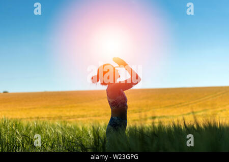 Frau, die in einem Feld meditieren mit Sonne in den Himmel, Yoga dar. Stockfoto