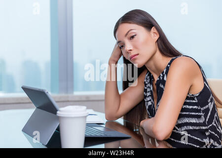 Gelangweilt oder traurige Frau im Büro Job arbeiten. Negative arbeit Konzept. Müde geschäftsfrau am Schreibtisch sitzen vor dem Laptop Nachdenken über Probleme und Unzufriedenheit der Karriere. Stockfoto
