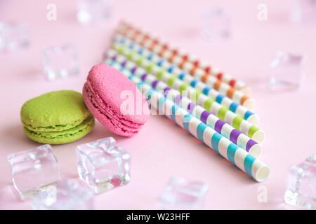 In der Nähe der bunten Trinkhalmen und Eiswürfel mit schönen Makronen Cookies auf Pastell rosa Hintergrund minimal kreativen Sommer essen und trinken r Stockfoto