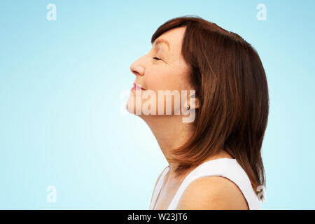 Profil von lächelnden älteren Frau über Blau Stockfoto