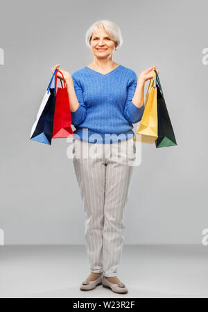 Ältere Frau mit Einkaufstüten über Grau Stockfoto