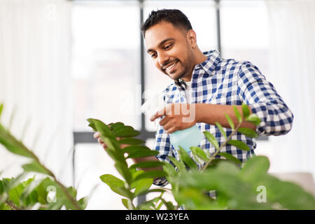 Indische Mann spritzen Zimmerpflanze mit Wasser zu Hause Stockfoto