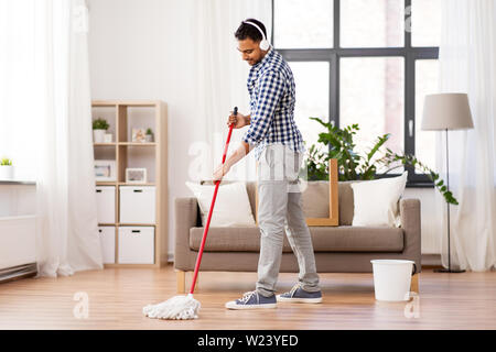 Mann in Kopfhörer mit Mop Reinigung Boden zu Hause Stockfoto