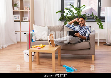Mann mit Tablet Computer nach Hause Reinigung Stockfoto