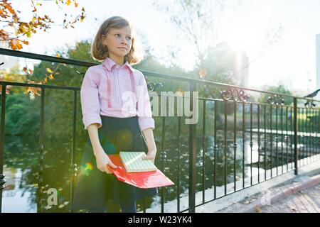 Zurück zu Schule, kleine Mädchen mit Schulheften im Herbst sonnigen Park. Stockfoto