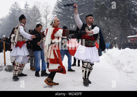 Razlog, Bulgarien - 12. Januar 2019: Menschen in bulgarischen Volkstrachten tanzen auf den verschneiten Straßen von Razlog während des Volksfestes in Starchevata Stockfoto