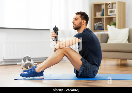 Man Trinkwasser beim Training zu Hause Stockfoto