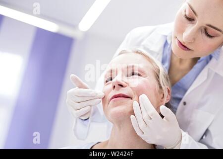 Junge weibliche Arzt prüft das Gesicht des Patienten. Stockfoto