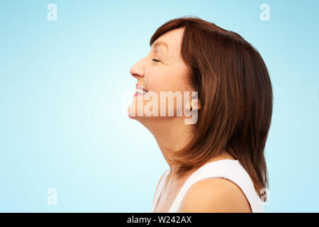 Profil von lächelnden älteren Frau über Blau Stockfoto