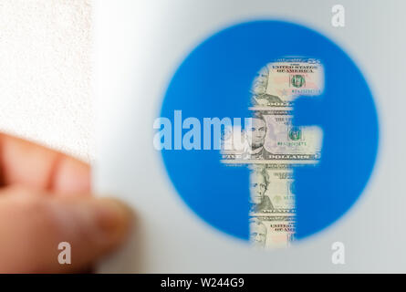 Dollar Bill durch transparentes Logo von Facebook auf einer gedruckten Broschüre gesehen. Konzeptionelle Foto für Facebook Waage - Neue Facebook Geld. Stockfoto