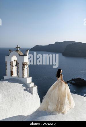 Griechenland, Santorini, Oia. September 16, 2014: Braut in eine schöne Hochzeit zu planen steht auf dem Dach des Hauses und genießt die Aussicht auf das Meer und Himmel ein Stockfoto