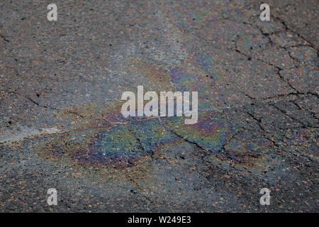 Nahaufnahme der irisierende Öl oder Benzin auslaufen auf einem nassen Asphalt. Winkel geneigt, konzentrierte sich auf den Vordergrund. Stockfoto