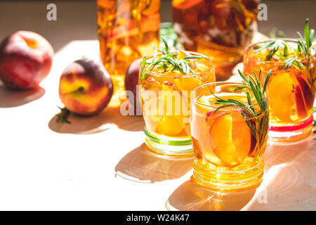 Gläser süßer Pfirsich Eistee, Sommer kalt Pfirsich fizz Cocktail mit Rosmarin. Sonnigen Licht. Geringe Tiefe des Feldes, Nahaufnahme, kopieren Sie Raum für Sie Stockfoto