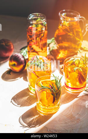 Gläser süßer Pfirsich Eistee, Sommer kalt Pfirsich fizz Cocktail mit Rosmarin. Sonnigen Licht. Geringe Tiefe des Feldes, Nahaufnahme, kopieren Sie Raum für Sie Stockfoto