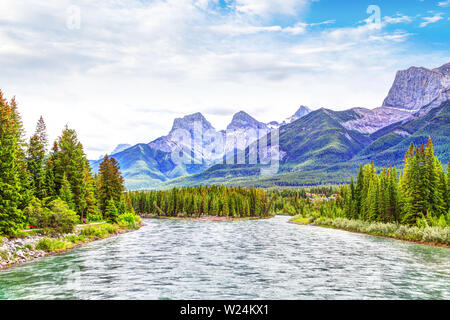 Bow River in Canmore mit der Kanadischen Rockies Bergketten der Drei Schwestern und Ehagay Nakoda im Hintergrund. Stockfoto