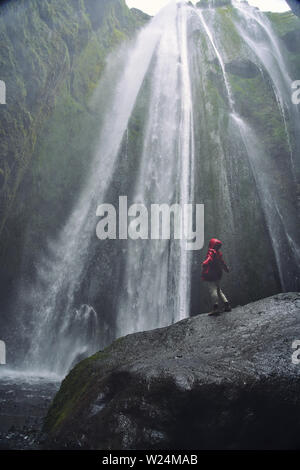 Eine Person admirnig die Schönheit der Skogafoss Wasserfall in Island entfernt) Stockfoto