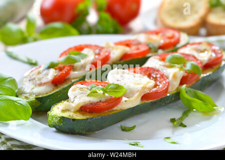 Gefüllte und Gebackene Zucchini mit Tomaten, Mozzarella und Basilikum mit Kraut Baguette serviert. Stockfoto