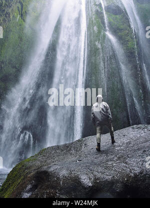 Eine Person admirnig die Schönheit der Skogafoss Wasserfall in Island entfernt) Stockfoto