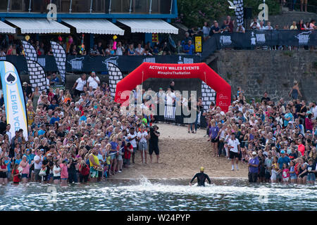 Tenby, Pembrokeshire, West Wales, UK. Vom 5. Juli 2019. Lange Wochenende. Über 10.000 Teilnehmer aus 45 Nationen nehmen an der jährlich stattfindenden Veranstaltung in einer der härtesten Kurse. Rund 35000 Zuschauern sammeln die Schwimmen an diesem Abend zu unterstützen. Die elektrischen Atmosphäre wurde besser durch das herrliche Wetter. Credit: Andrew Bartlett/Alamy leben Nachrichten Stockfoto