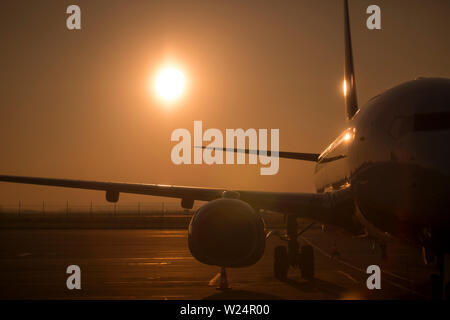 Große Verkehrsflugzeuge im Abend Licht warten auf Flug an Runaway beleuchtet von Golden Sun Hintergrundbeleuchtung niedrig am Himmel vor Sonnenuntergang. Stockfoto