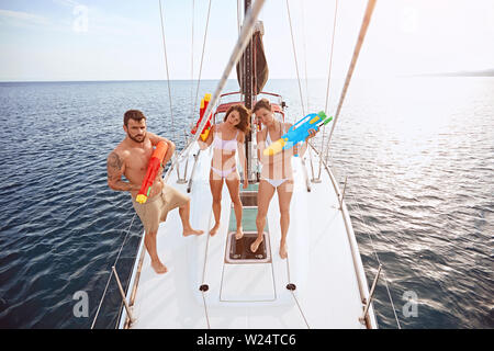 Junge Menschen spielen auf Segelboot mit Wasserpistolen. Stockfoto