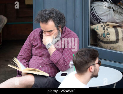 Mann lesen Buch Outside cafe Stockfoto