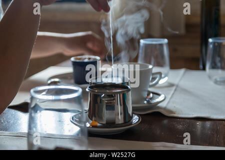 Kleine Teekanne mit Teebeutel, einige Gläser auf dem Tisch im Restaurant. Weißer Dampf steigt über heißes Wasser. Selektive konzentrieren. Stockfoto