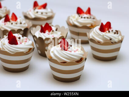 Close-up kleine Kuchen mit Schlagsahne eier Creme frische Erdbeeren und Schokolade Kugeln auf weißem Hintergrund. Isolieren Stockfoto