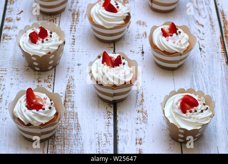 Close-up kleine Kuchen mit Schlagsahne eier Creme frische Erdbeeren und Schokolade Kugeln auf alte weiße Holztisch Hintergrund. Stockfoto