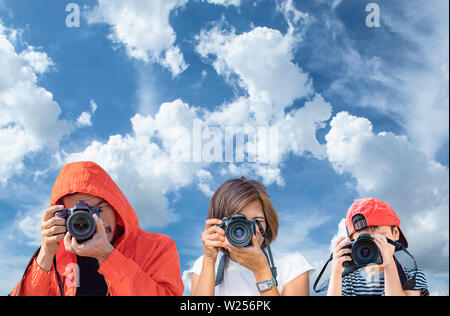 Hand Mann, Frau und Jungen Halten der Kamera die Bilder im Hintergrund Himmel und Wolken Stockfoto