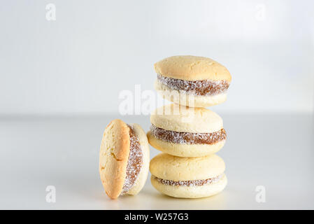 Alfajores mit köstlichen argentinischen Cookies Cream dulce de leche Close-up auf den Tisch. Weiße Vanille Makronen auf weißem Hintergrund. Französische zarte Dessert für Frühstück im Morgenlicht. Stockfoto