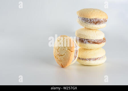 Alfajores mit köstlichen argentinischen Cookies Cream dulce de leche Close-up auf den Tisch. Weiße Vanille Makronen auf weißem Hintergrund. Französische zarte Dessert für Frühstück im Morgenlicht. Stockfoto