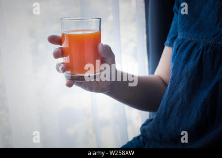 Weibliche Hand, die eine Tasse Orangensaft morgens, wenn Sie aufwachen. gesunder Lebensstil Konzept Ideen Stockfoto