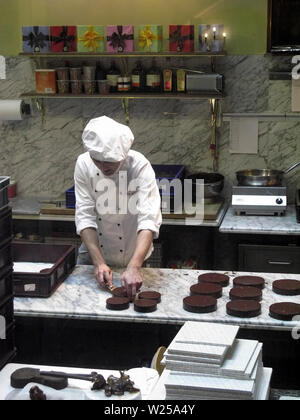 Junge Küchenchef Vorbereitung Sacher Torte Kuchen in der Küche des Café Demel, Wien, Österreich Stockfoto