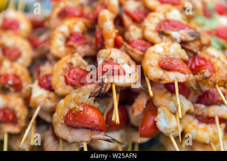 Köstliche Meeresfrüchte leckere Spieße mit Garnelen mit Tomaten cherry, aufgereiht auf Holzstäbchen Nahaufnahme. Stockfoto