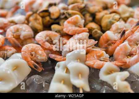 Köstliche Meeresfrüchte leckere Spieße mit Garnelen mit Tintenfisch und Muscheln, aufgereiht auf Holzstäbchen auf Eis Nahaufnahme. Stockfoto