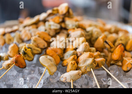 Köstliche Meeresfrüchte leckere Spieße mit Muscheln, aufgereiht auf Holzstäbchen auf Eis Nahaufnahme. Stockfoto