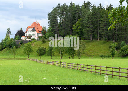 Bayern, Deutschland - Apr 2017: Gemütliches, traditionelles Alpine House auf einem üppigen grünen Rasen in die Bayerischen Alpen. Stockfoto