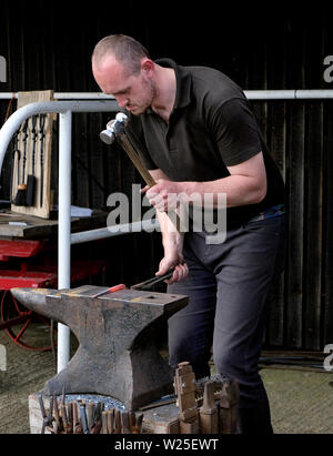 Schmied bei der Arbeit bilden, heißes Metall nach Heizung in einer Schmiede. Stockfoto