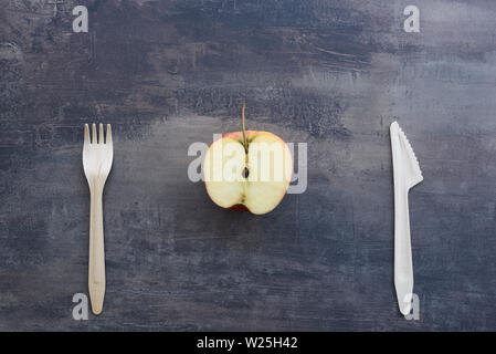 Blick von oben auf die Gabel, Messer und Apple in der Hälfte, auf dem Hintergrund von Marmor Arbeitsplatte in der Küche. Natürliche Holz Besteck. Stockfoto