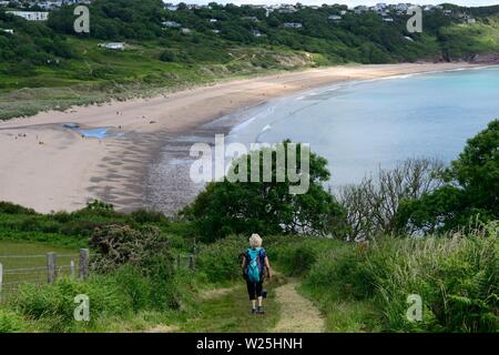 Frau zu Fuß auf den Pembrokeshire Coast Path in Richtung Süßwasser East Beach Pembrokeshire Wales Cymru GROSSBRITANNIEN Stockfoto