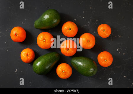 Von oben nach unten - avocados und Mandarinen auf Schwarz arbeiten mit Marmoreffekt Stockfoto