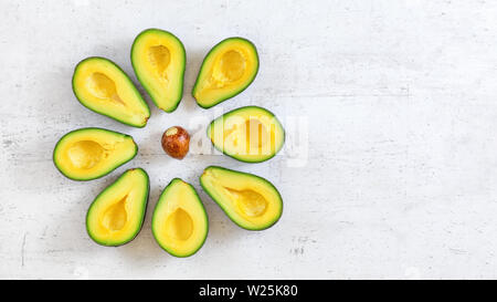 Avocado Hälften im Kreis angeordnet, braune Saat in der Mitte, auf dem Whiteboard Schreibtisch, Overhead shot Stockfoto