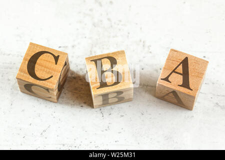 Drei Holzwürfel mit Buchstaben CBA steht für die Kosten-Nutzen-Bewertung auf dem Whiteboard. Stockfoto