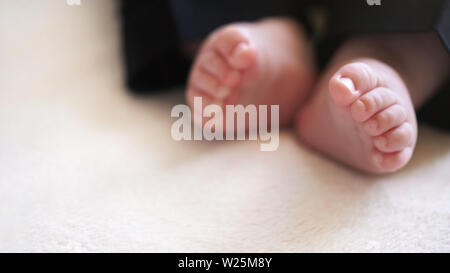 Kind Baby Junge Beine in kleinen schwarzen Hosen, Weichzeichner Foto mit Detail auf seine Füße, Platz für Text unten links Stockfoto